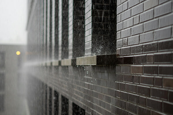 Heavy rain striking the brick exterior and windows of a commercial building