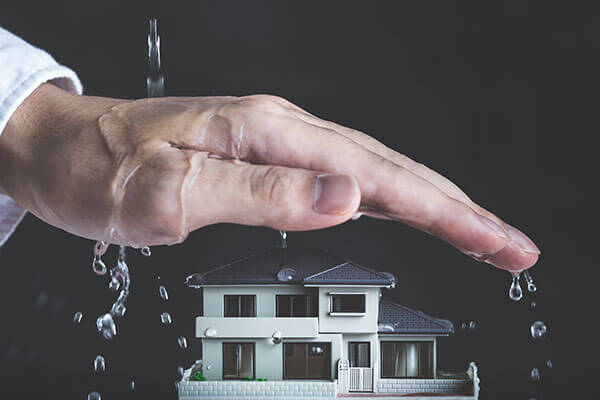 Hand covering house to depict coverage Flooded basement cleanup Colorado Springs, CO