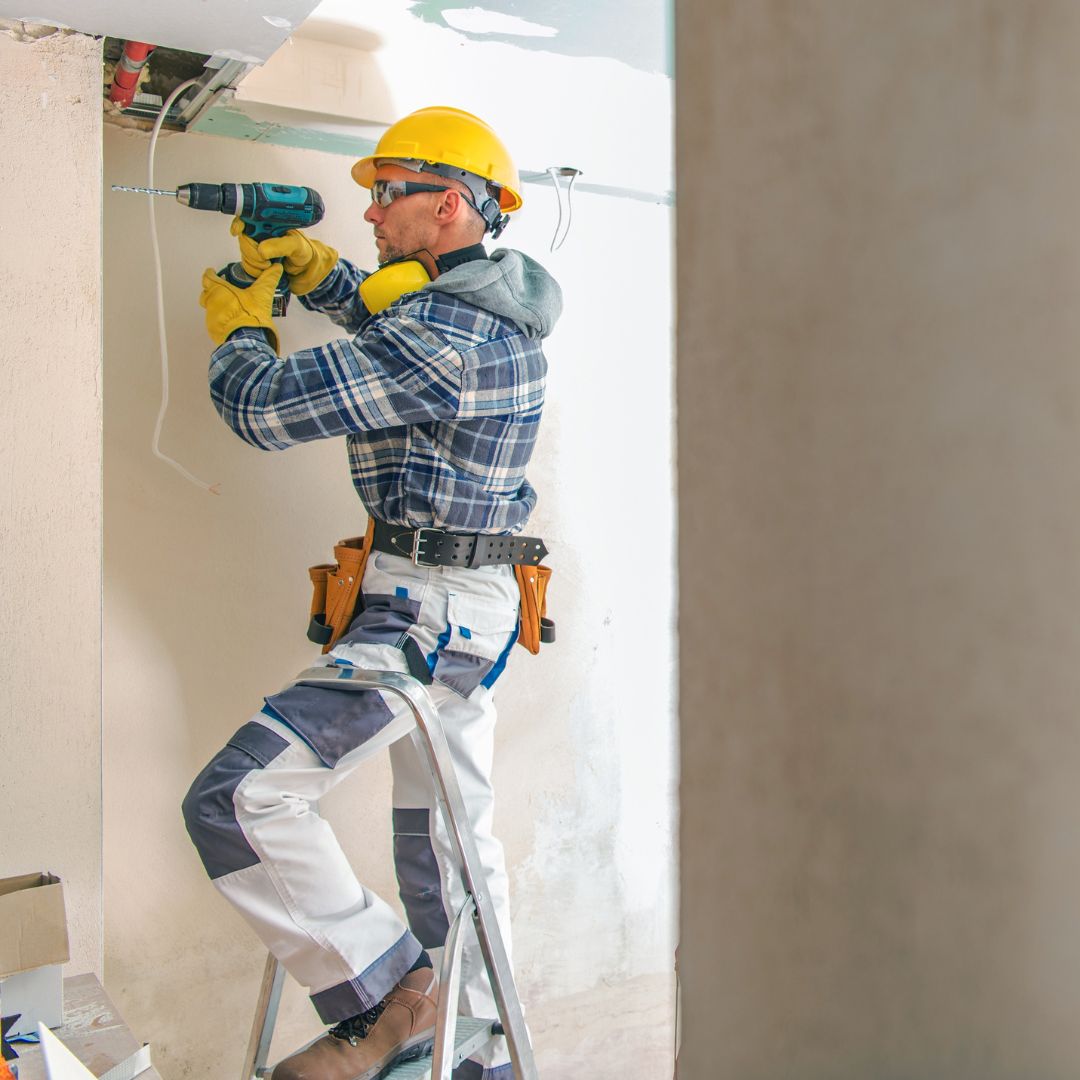 A contractor using a drill on a wall