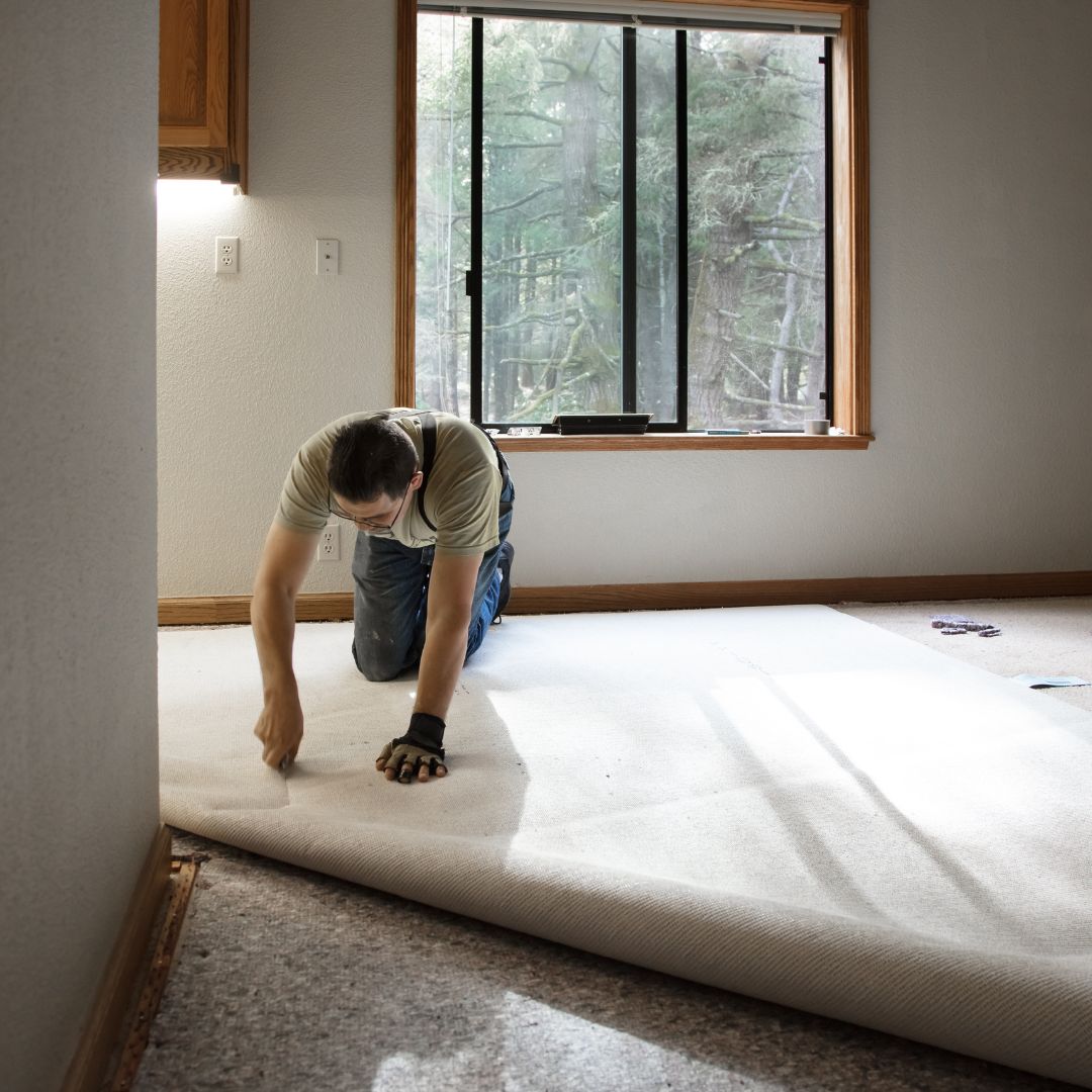 A man installing carpet in a house