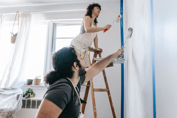 Boost your home's value with these simple yet impressive renovations. A couple painting their home and working on essential pre-sale renovations.